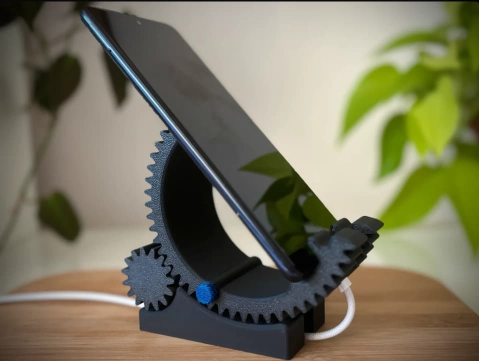 CogForm holding a phone upright while a white charging cable passes through the base